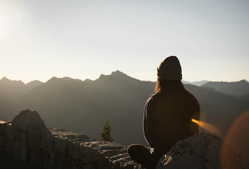 A person looking over a peaceful mountain landscape at sunrise